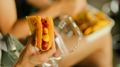 Close-up of a hot dog with mustard and ketchup held in hand, perfect street food meal.