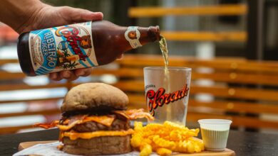 A casual dining setup with a burger, fries, and craft beer being poured into a glass.