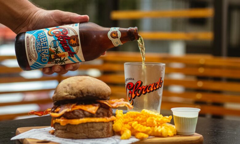 A casual dining setup with a burger, fries, and craft beer being poured into a glass.