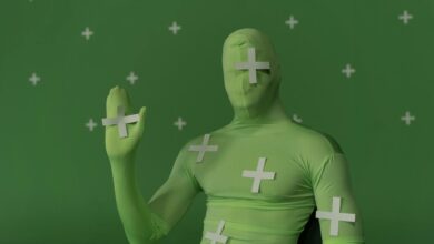 Person wearing a green screen suit with tracking markers for visual effects work.