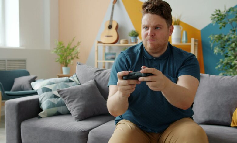Focused young man enjoying gaming at home with a console in a stylish living room.
