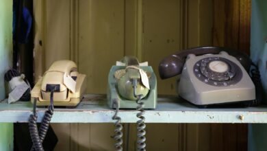 Collection of vintage rotary and push-button telephones on a shelf.