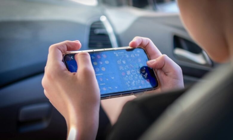 A teenager plays a mobile game while sitting inside a car, showcasing modern technology engagement.