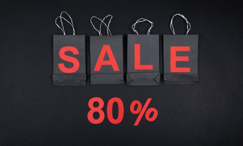 Highlighting a sale with 80% discount using black shopping bags and bold red text.