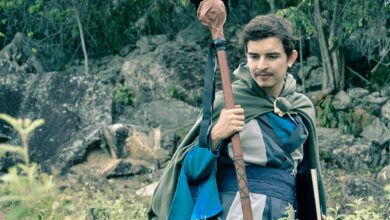 Man wearing medieval cosplay costume holding staff in a forest setting in Colombia.