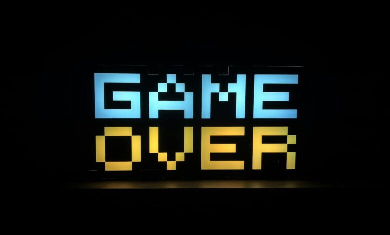 Illuminated pixel art 'Game Over' sign with vibrant colors against a black background.