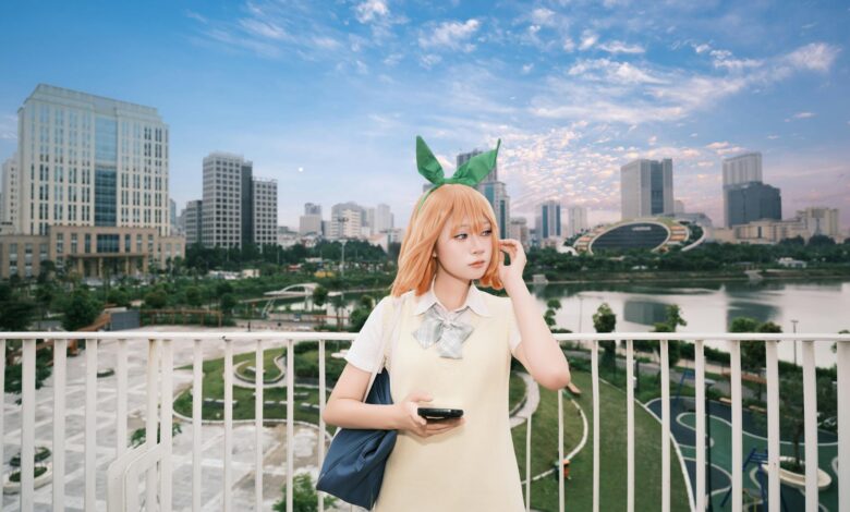 A cosplayer dressed as an anime character poses in a modern city park with a skyline backdrop.
