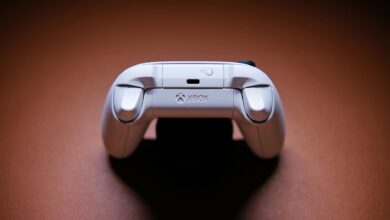 A white Xbox game controller beautifully captured on a light brown background, showcasing modern gaming technology.