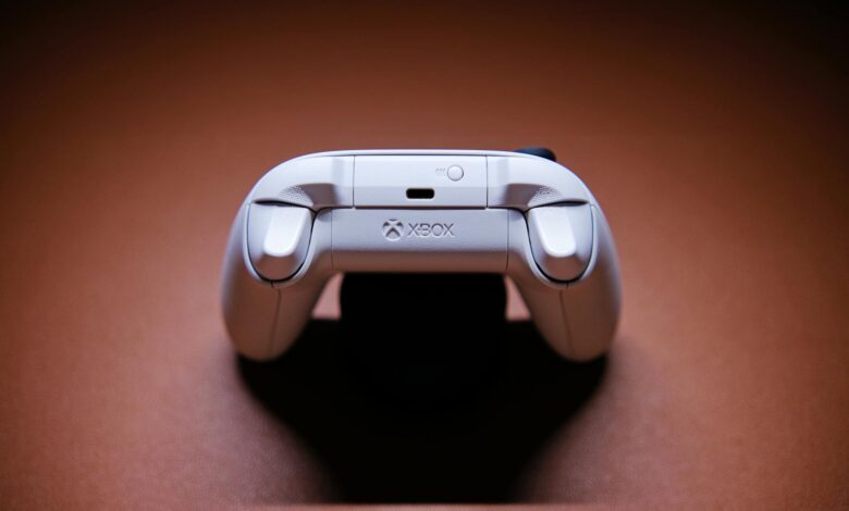 A white Xbox game controller beautifully captured on a light brown background, showcasing modern gaming technology.