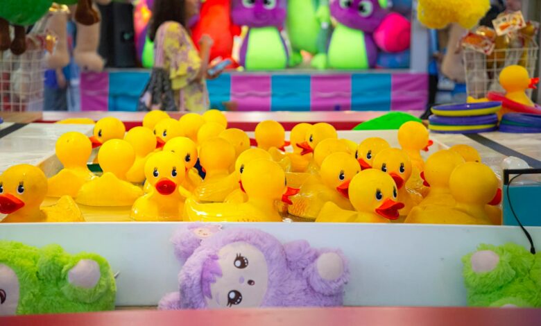 Colorful carnival game with yellow rubber ducks and vibrant plush toys in the background.