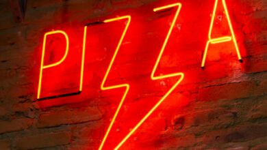 Bright red neon 'Pizza' sign on a rustic brick wall, perfect decor for pizzerias.