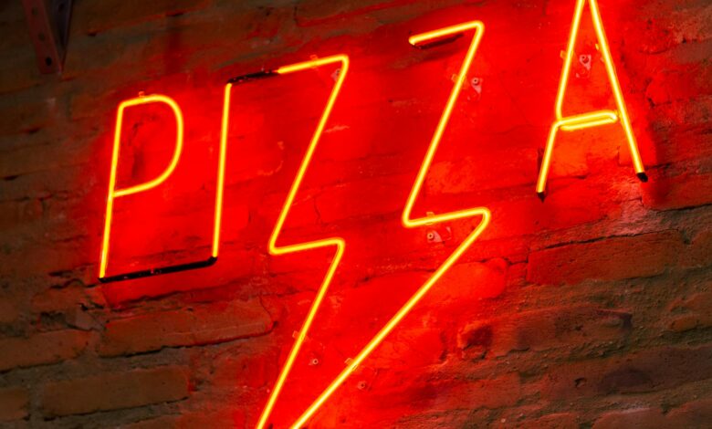 Bright red neon 'Pizza' sign on a rustic brick wall, perfect decor for pizzerias.