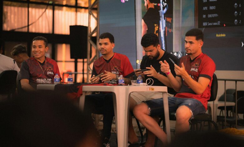 A group of e-sports players participating in a gaming event, focused on smartphone gameplay.