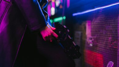Person holding a futuristic gun with vibrant neon cyberpunk aesthetics.