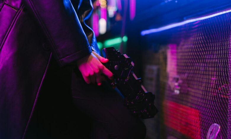 Person holding a futuristic gun with vibrant neon cyberpunk aesthetics.