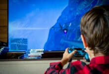 Young boy playing video game on TV with PS4 controller, enjoying leisure time indoors.