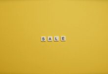 Single word 'SALE' spelled with tiles on a bright yellow background, ideal for advertising.