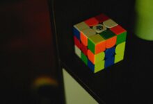 A vibrant Rubik's Cube sits on a dark shelf, showcasing its colorful puzzle design.