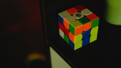A vibrant Rubik's Cube sits on a dark shelf, showcasing its colorful puzzle design.