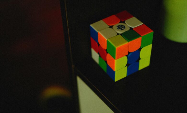 A vibrant Rubik's Cube sits on a dark shelf, showcasing its colorful puzzle design.