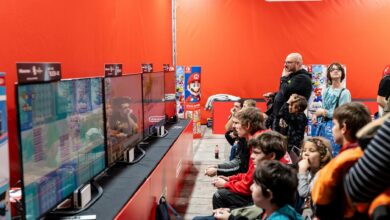 A lively group enjoys gaming at a Nintendo event in Zagreb, featuring multiple screens and vibrant atmosphere.