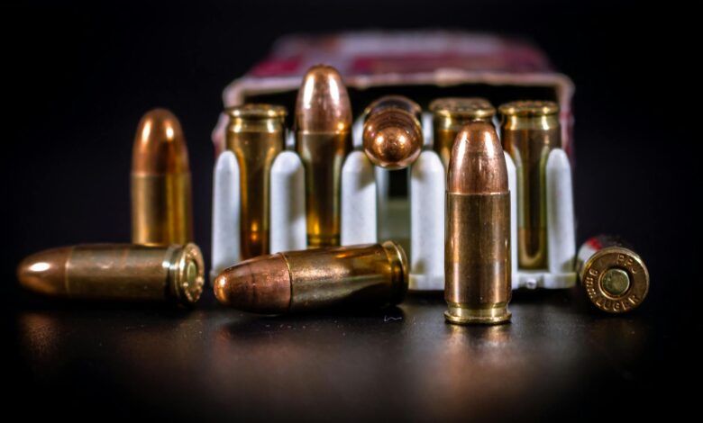 Detailed close-up of copper ammunition bullets in a cardboard box on black background.