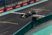 Formula 1 car speeding across the finish line on a racetrack, emitting sparks.