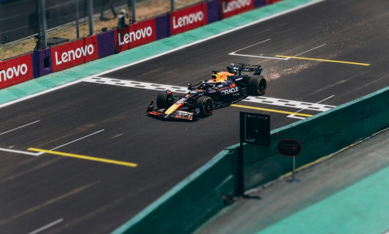 Formula 1 car speeding across the finish line on a racetrack, emitting sparks.