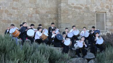 Group of boys playing drums against a historic stone wall outdoors.