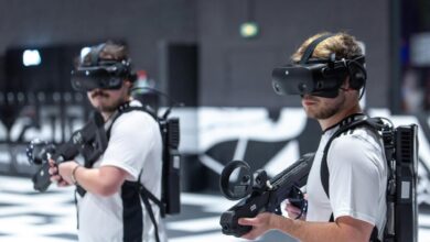 Two men playing a virtual reality game indoors in Paris, using VR headsets and gear.
