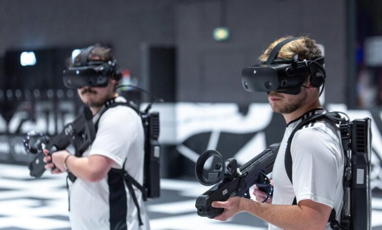 Two men playing a virtual reality game indoors in Paris, using VR headsets and gear.