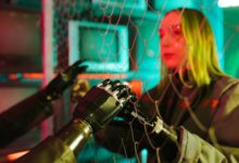 A woman interacts with robotic hands through a mesh displaying a neon cyberpunk atmosphere.
