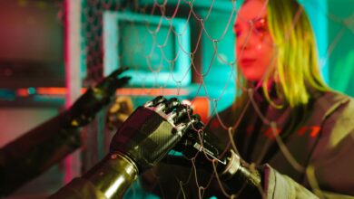 A woman interacts with robotic hands through a mesh displaying a neon cyberpunk atmosphere.
