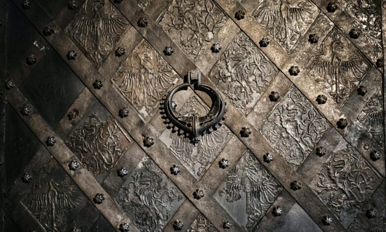 Close-up of a detailed metal door in Nuremberg, Germany displaying ornate medieval designs and a circular handle.