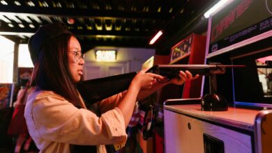 Teenage girl having fun playing a shooting game at an arcade, representing youthful playfulness.