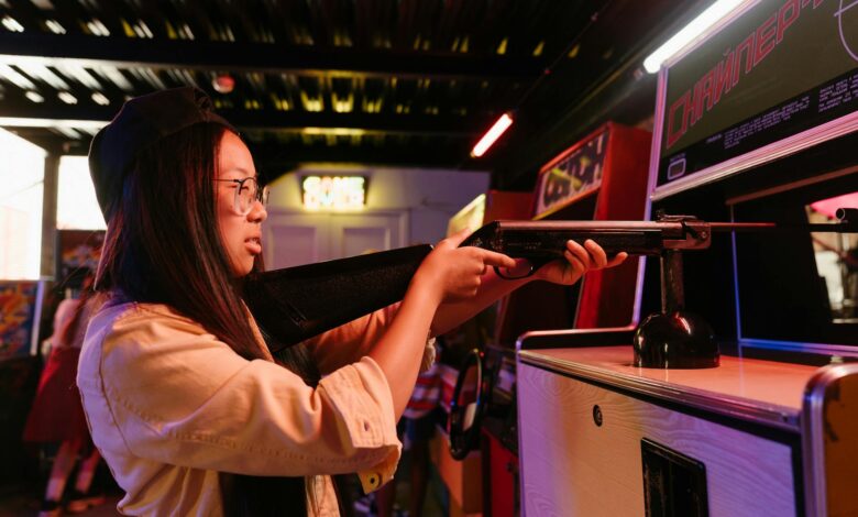 Teenage girl having fun playing a shooting game at an arcade, representing youthful playfulness.