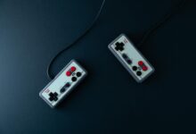 Top view of two retro gaming controllers on a minimalist dark background.