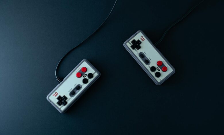 Top view of two retro gaming controllers on a minimalist dark background.