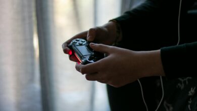 Close-up of hands holding a video game controller in a dimly lit room.