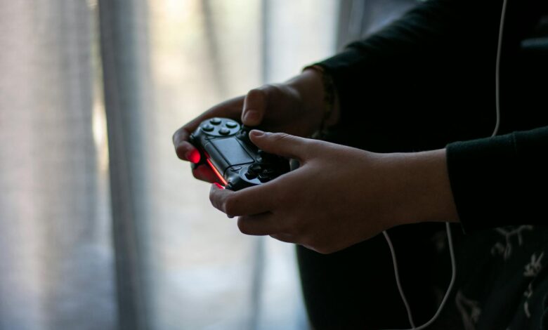 Close-up of hands holding a video game controller in a dimly lit room.