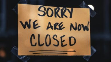 A handwritten sign with 'Sorry We Are Now Closed' in a dark window setting.
