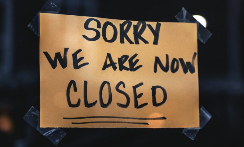 A handwritten sign with 'Sorry We Are Now Closed' in a dark window setting.
