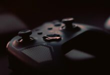 A close-up shot of a game controller in low light, highlighting its design and buttons.
