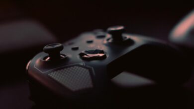 A close-up shot of a game controller in low light, highlighting its design and buttons.