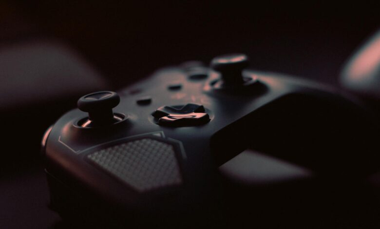 A close-up shot of a game controller in low light, highlighting its design and buttons.