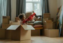 A child enjoying playtime with a toy gun amidst moving boxes, indoors.