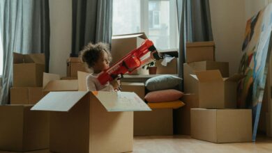 A child enjoying playtime with a toy gun amidst moving boxes, indoors.