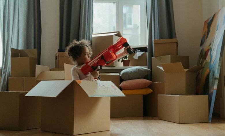 A child enjoying playtime with a toy gun amidst moving boxes, indoors.