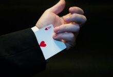 A magician's hand showing an ace of hearts hidden up the sleeve, symbolizing magic and trickery.