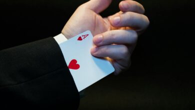 A magician's hand showing an ace of hearts hidden up the sleeve, symbolizing magic and trickery.